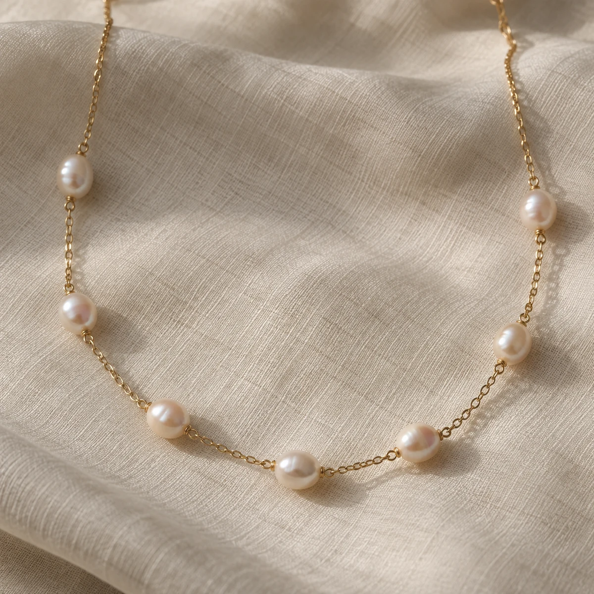 Freshwater pearl station necklace arranged on ivory silk; concept photograph